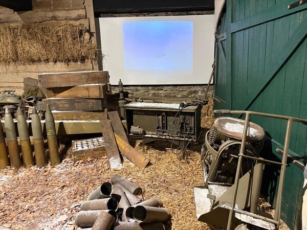 Museum diorama of an ammunition dump with shells, spent cases and wooden crates on straw in a barn